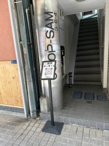 建物の入口から上階へ続く階段。入口脇に看板が見える。